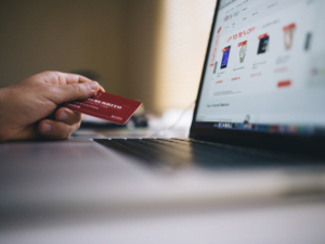person holding their credit card up next to their laptop